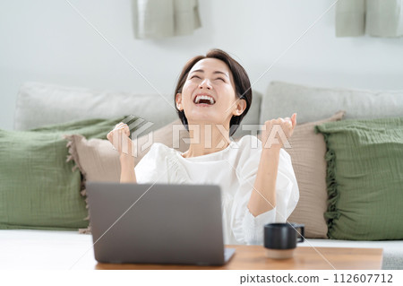 一個女人看著電腦，揮舞著拳頭 112607712