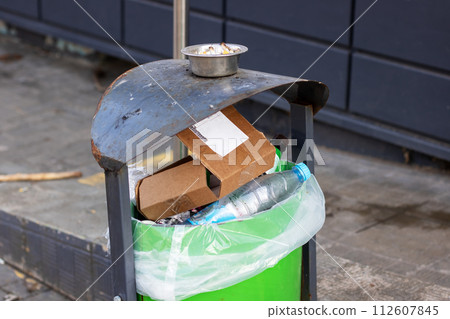 Black big garbage cans on asphalt closeup Black big garbage cans on asphalt closeup 112607845
