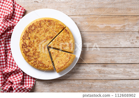 Traditional spanish omelette with ingredients on wooden table.. 112608902