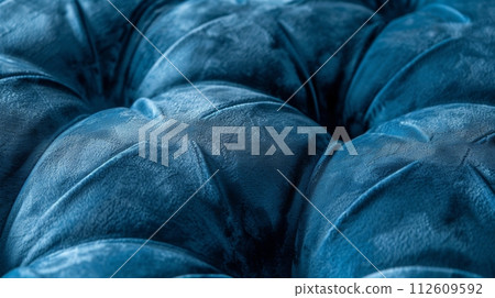 Luxurious blue velvet tufted upholstery, showcasing the intricate details and rich texture. 112609592