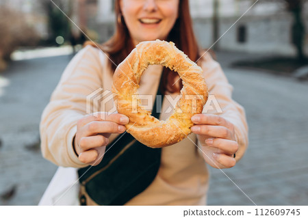 Woman holds a traditional Turkish simit in hands. Selective focus. High quality photo Woman holds a traditional Turkish simit in hands. Selective focus. High quality photo 112609745