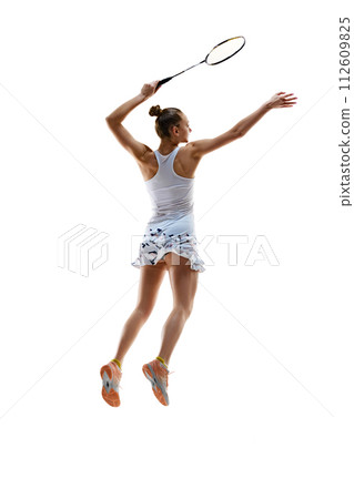 Back view of muscular young girl, badminton player in motion hitting shuttlecock with racket isolated over white background 112609825