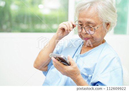 Asian senior woman wearing eyeglasses or vision glasses using a smartphone at home care service. Asian senior woman wearing eyeglasses or vision glasses using a smartphone at home care service. 112609922