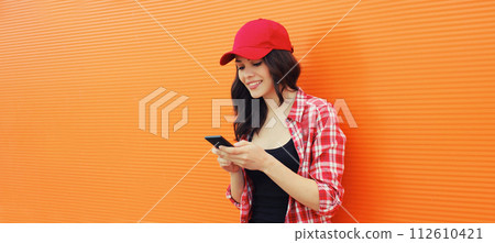Portrait of happy smiling young woman with mobile phone on colorful orange background Portrait of happy smiling young woman with mobile phone on colorful orange background 112610421