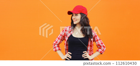 Summer portrait of happy smiling young woman posing in red baseball cap, casual clothes 112610430