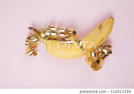 a ripe banana wrapped in a golden curled ribbon as if it were a gift 112611589