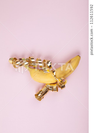 a ripe banana wrapped in a golden curled ribbon as if it were a gift 112611592