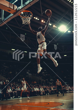 A dynamic image capturing a basketball player mid-air about to dunk during a game A dynamic image capturing a basketball player mid-air about to dunk during a game 112612215