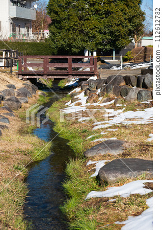 A snowy stream between roadside stations 112612782