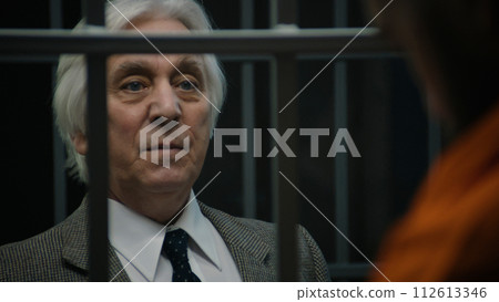 Lawyer talks with criminal standing in prison cell, offers his services Lawyer talks with criminal standing in prison cell, offers his services 112613346