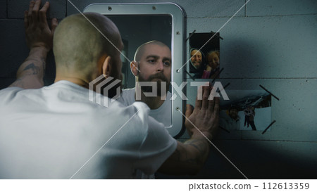 Inmate looks at the pictures with family hanging near the mirror Inmate looks at the pictures with family hanging near the mirror 112613359