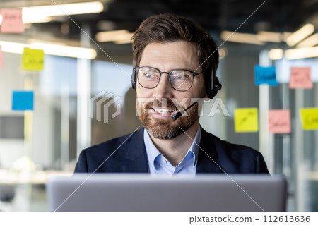 Confident business professional engaging in a video conference call with a headset in a modern office setting. 112613636