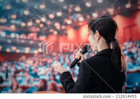 一位女士在一大群觀眾面前發表演講 一位女士在一大群觀眾面前發表演講 112614455