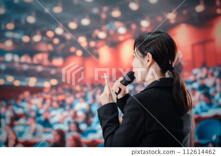 A woman giving a speech in front of a large audience 112614462