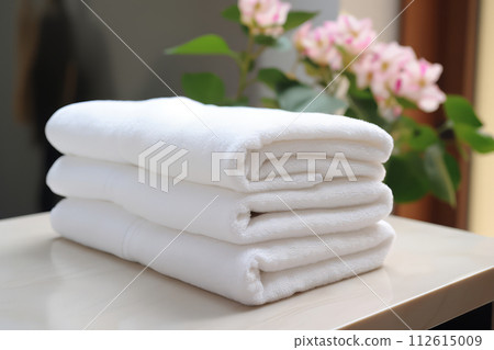A stack of clean cotton towels on a table in the bathroom. White terry towels. 112615009