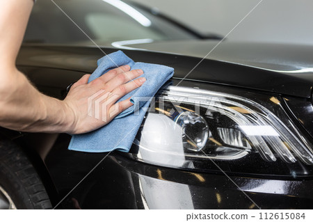 Young man hand cleaning the headlamp of the modern car in detailing studio, detail the car concept 112615084