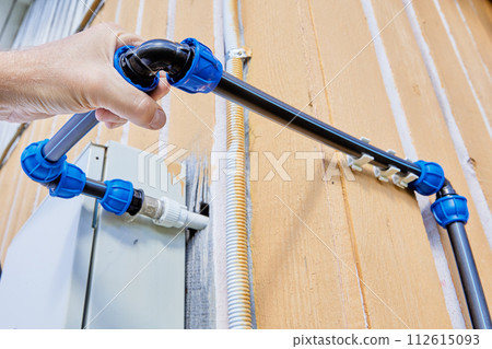 Installing an outdoor pipeline for drinking water and irrigation, plumber tightens elbow compression fitting nut. Installing an outdoor pipeline for drinking water and irrigation, plumber tightens elbow compression fitting nut. 112615093