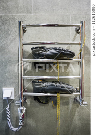 Hiking shoes drying after big camping. Black boots for hiking lying on dryer in bathroom. Hiking shoes drying after big camping. Black boots for hiking lying on dryer in bathroom. 112616090