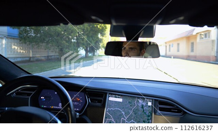 Eyes of male driver reflecting of rearview mirror during riding electrical auto. Confident man driving a modern car at city. Young guy looking concentrated to urban road during operating vehicle Eyes of male driver reflecting of rearview mirror during riding electrical auto. Confident man driving a modern car at city. Young guy looking concentrated to urban road during operating vehicle 112616237