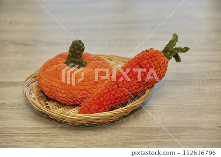 Cute knitted vegetables toys on a wicker plate 112616796