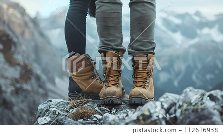 Close-up of two pairs of legs wearing hiking boots on a mountain peak. adventurous spirits exploring the wilderness. outdoor lifestyle captured in nature's embrace. AI 112616938