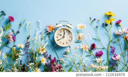 Vintage alarm clock surrounded by colorful wildflowers on blue backdrop. time concept in nature. simple, creative, and fresh. AI 112616978