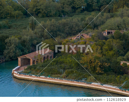 Aerial view of the plagued ghost island of Poveglia in the Venetian lagoon, opposite Malamocco along the Canal Orfano near Venice, Italy. 112618929