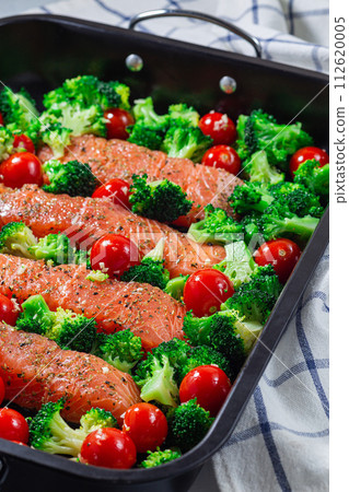 Raw salmon fillet with broccoli and tomato on frying tray, ready to bake, vertical Raw salmon fillet with broccoli and tomato on frying tray, ready to bake, vertical 112620005