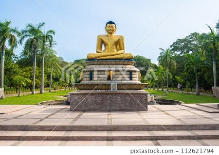 An iconic golden Buddha statue in Viharamahadevi Park a public park located in Colombo, Sri Lanka. Viharamahadevi park is the oldest and largest park of the Port of Colombo. 112621794