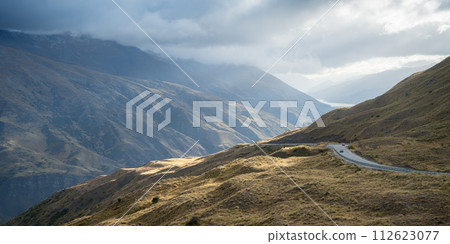 Cars passing curvy road leading through mountains pass in alpine environment, New Zealand Cars passing curvy road leading through mountains pass in alpine environment, New Zealand 112623077
