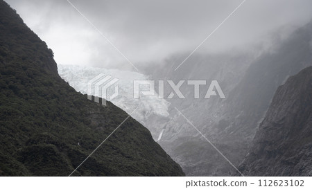Massive glacier flowing into a valley through steep rock walls shot in New Zealand Massive glacier flowing into a valley through steep rock walls shot in New Zealand 112623102