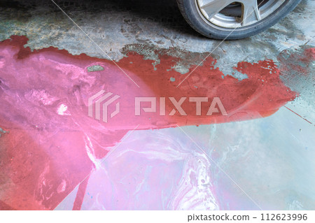 puddle of pink coolant and brown technical liquids on the concrete floor near car puddle of pink coolant and brown technical liquids on the concrete floor near car 112623996