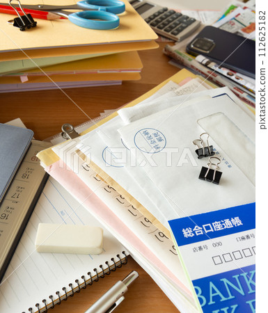 Desk scattered with accumulated documents and mail, cluttered desk, clutter Desk scattered with accumulated documents and mail, cluttered desk, clutter 112625182