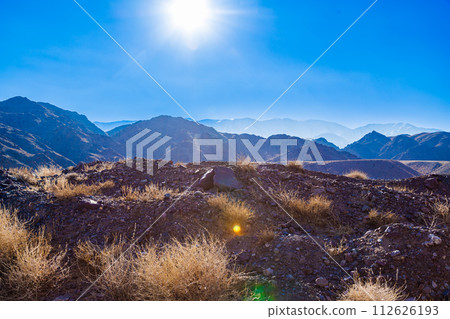 rocks and dry grass tufts in autumn mountains backlit scene at sunny day 112626193