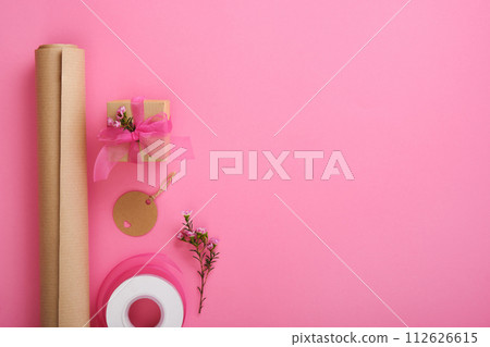 Gift wrapping. Brown craft wrapping paper, black ribbon, scissors, waxflower, tags. Copyspace 112626615