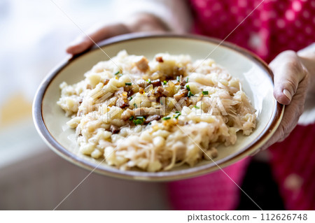 The hands of a senior home cook hold a plate with a national Slovak dish 112626748