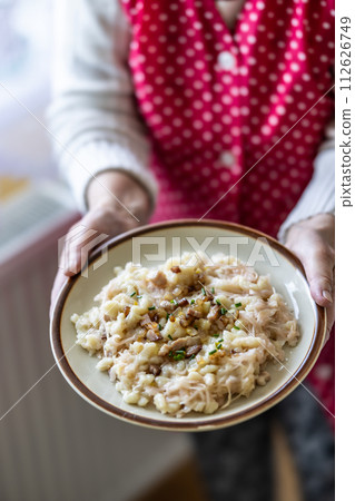 The hands of a senior home cook hold a plate with a national Slovak dish 112626749