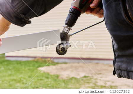 Gears for cutting sheet metal are rotated using an electric drill, being an adapter attachment, roofer cuts roofing steel outdoors. 112627332