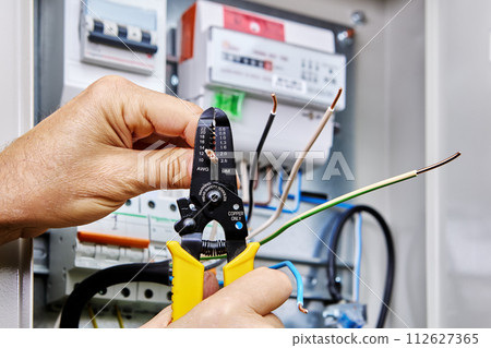 Tool for stripping wires is used when installing an outdoor electrical panel with an electricity meter and circuit breakers. Tool for stripping wires is used when installing an outdoor electrical panel with an electricity meter and circuit breakers. 112627365
