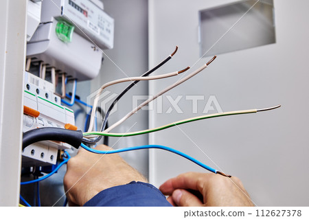 Electrician prepared three-phase power cable for connection in external electrical panel. 112627378