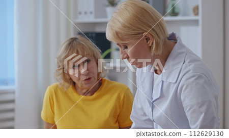 A traumatologist consults with a female patient about broken bone treatment, focusing on rehabilitation 112629130