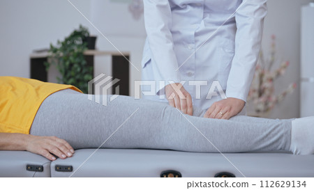 A doctor examines a patient's knee in a hospital, treating arthritis and aiding rehabilitation 112629134