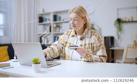 Woman entering credit card number on laptop website to pay for purchases online Woman entering credit card number on laptop website to pay for purchases online 112629246