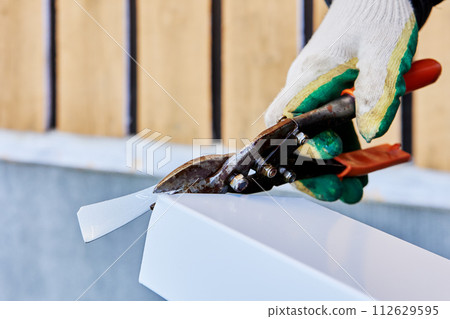 Sheet metal snips for right handed cutting, roofer cuts edge of window slope made of galvanized steel. Sheet metal snips for right handed cutting, roofer cuts edge of window slope made of galvanized steel. 112629595