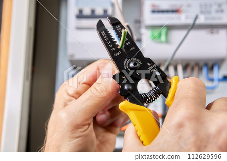 Using wire cutter stripping tool for removal insulation of copper wire from three-phase, four-core cable. 112629596