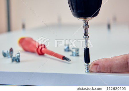 Furniture fixings dowel bolts for cam locks screws connector, installer screws connection screw into chipboard panel using an power screwdriver. 112629603