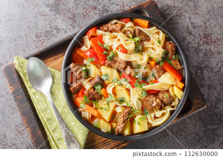 Asian Lagman soup with lamb, homemade noodles and vegetables closeup on the plate. Horizontal top view Asian Lagman soup with lamb, homemade noodles and vegetables closeup on the plate. Horizontal top view 112630000