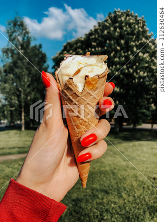 woman hand holding ice-cream at summer sunny day close up. natural green background. 112630464