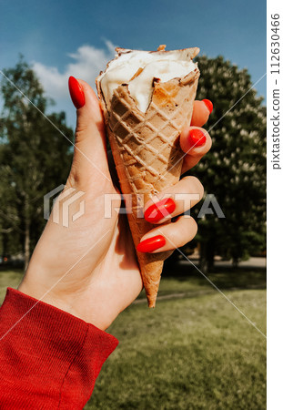 woman hand holding ice-cream at summer sunny day close up. natural green background. 112630466