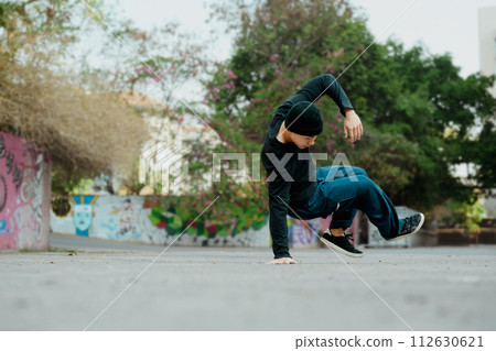 Full length shot of attractive male practicing b-boy dance on the street Full length shot of attractive male practicing b-boy dance on the street 112630621